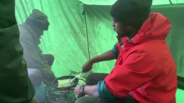 Dağlardaki çadır mutfağı. Karizmatik bir siyah aşçı çadırda bir tavada sıcak sandviçler hazırlar. Aralık 'ta Kilimanjaro' ya tırmanmak, Tanzanya, Afrika.