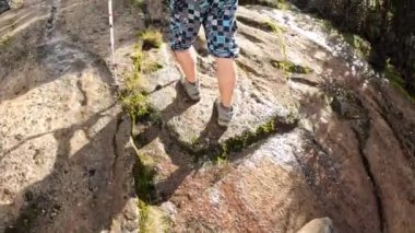 Turistler kayalık bir yüzeyde yokuş yukarı tırmanırlar. Arkadan bacaklara bak. Dağ manzarası. Kilimanjaro 'ya tırmanmak.