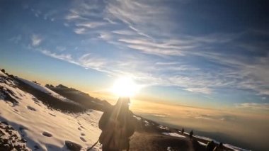 Kilimanjaro Dağı 'nın tepesinden inanılmaz bir gün doğumu. Küçük gruplar halinde turistler Kilimanjaro 'ya tırmanıyor. Güzel dağ manzarası. Çarpıcı mavi gökyüzü ve beyaz bulutlar.