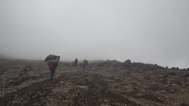 Kilimanjaro, Tanzanya - 1 Ocak 2022: Hamallar dağ yolunda yürür. Zayıflayan turist hastaneye sedyeyle getirildi. Sisli dağ manzarası. Kilimanjaro 'ya tırmanmak.
