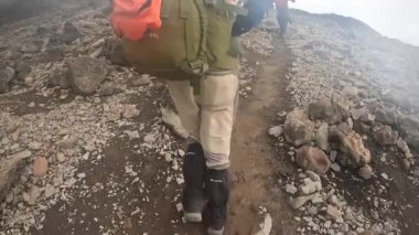 Kilimanjaro, Tanzanya - 31 Aralık 2021: Bir grup turist, rehber ve hamal kayalık bir yoldan dağa tırmanıyor. Sisli dağ manzarası. Kilimanjaro 'ya tırmanmak.