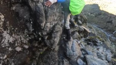 Kilimanjaro, Tanzanya - 30 Aralık 2021: Barranco Duvarındaki Meşhur Öpüşme Taşı. Siyah bir rehber tehlikeli dağlık bölgede turistlerine yardım ediyor. Kilimanjaro 'ya tırmanmak.