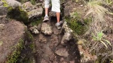 Büyük sırt çantalı siyah bir adam büyük kayalara tırmanıyor. Arkadan bacaklara bak. Tırmanan Kilimanjaro, Tanzanya, Afrika.