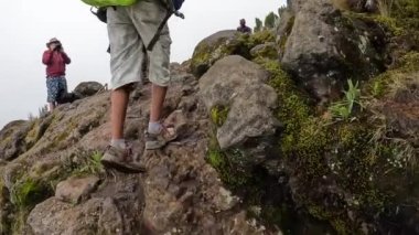 Kilimanjaro, Tanzanya - 28 Aralık 2021: Beyaz bir adam, dağ yoluna tırmanan büyük bir sandık ve sırt çantalı bir rehber ile siyah bir hamalın fotoğrafını çekiyor. Kilimanjaro 'ya tırmanmak.