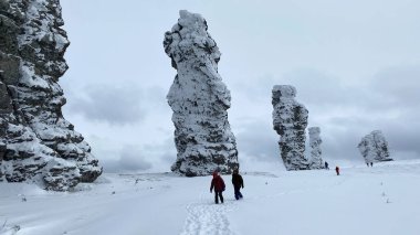 A group of tourists walks along the Manpupuner Plateau, Komi Republic, Russia. Weathering pillars. Geological monument in the Troitsko-Pechora region. One of the seven wonders of Russia.