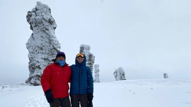 A guy and a girl are standing on the Manpupuner plateau. Weathering pillars in the Komi Republic, Russia. One of the seven wonders of Russia. Geological monument in the Troitsko-Pechora region.