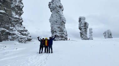 Three men are photographed near weathering pillars in the Komi Republic, Russia. Plateau Manpupuner. Geological monument in the Troitsko-Pechora region. One of the seven wonders of Russia.