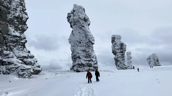 A group of tourists walks along the Manpupuner Plateau, Komi Republic, Russia. Weathering pillars. Geological monument in the Troitsko-Pechora region. One of the seven wonders of Russia.