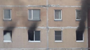Black smoke billows from three windows of an apartment building. Fire in the apartment. Extinguishing a fire in a high-rise building.