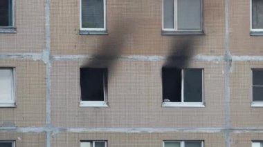 Close-up of black smoke coming out of the windows of two rooms in an apartment building. Fire in the apartment. Extinguishing a fire in a high-rise building.