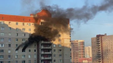 Fire in the apartment. Thick black smoke billows from two windows of an apartment building. Extinguishing a fire in a high-rise building.