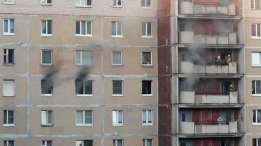St. Petersburg, Russia - June 28, 2022: Fire in the apartment. A group of firefighters are discussing a plan of action. Gray smoke is coming from several windows of an apartment building. Fire extinguishing.