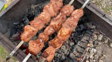 Summer vacation. Top view on fried three skewers with meat in a charcoal grill. Picnic in the country. Cooking barbecue.