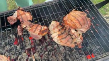 Summer holidays and vacations. Pieces of fried steak are turned over to the other side for better frying with iron tongs. Cooking barbecue. Picnic in the country. Grilled meat on charcoal grill.