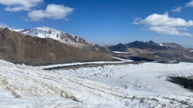 Beautiful mountain winter landscape. View of snow-capped mountains, rocks, hills and Camp 1 under Lenin Peak. The amazing nature of Kyrgyzstan.