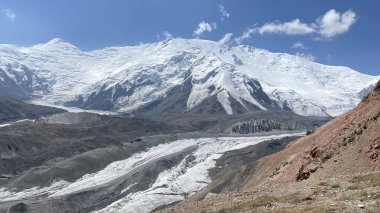 Amazing view of the snow-capped Pamir Mountains. Rocks, hills and glacier under Lenin Peak. Beautiful mountain landscape in Kyrgyzstan. The nature of the Pamirs.