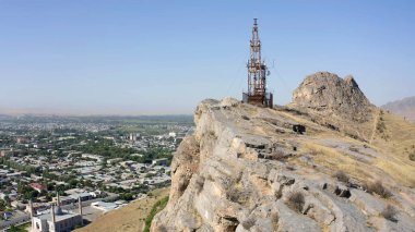 The cell tower stands on the rocky peak of the sacred mountain Sulaiman-Too. The city of Osh from a height. View of the amazing mountains. Beautiful nature of Kyrgyzstan.