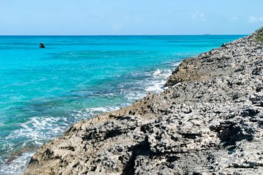 Yarım Ay Koyu 'ndaki keskin aşınmış kıyı şeridi ve turkuaz renkli sular (Bahamalar)).