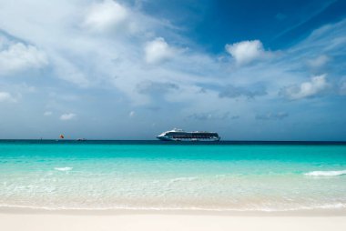 The turquoise color waters on Half Moon Cay island and a drifting cruise ship in a background (Bahamas).