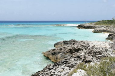 Half Moon Cay üzerinde kayalık bir kıyı şeridi ve turkuaz renkli suların manzarası (Bahamalar)).