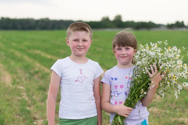 Boy and girl with a bouquet of daisies — Stock Photo, Image