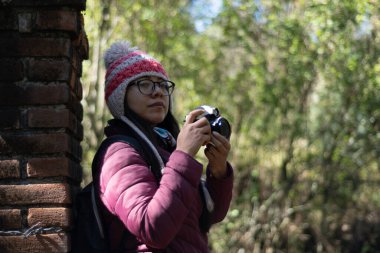 Doğanın ortasında kamera kullanan genç bir kadın.