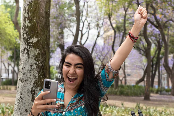 Parkta cep telefonunu kullanan genç bir kadın.