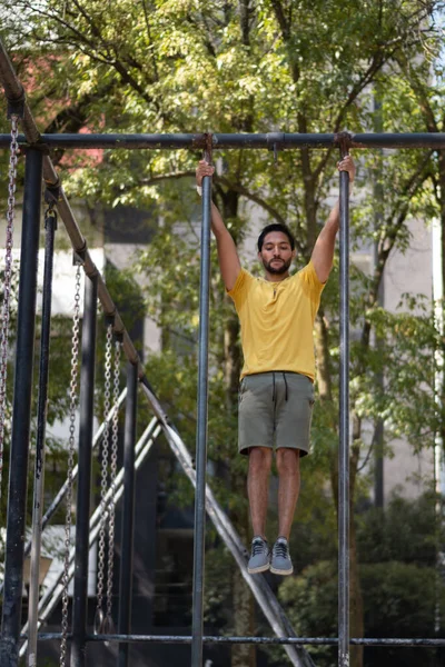 Genç adam parkta jimnastik yapıyor.