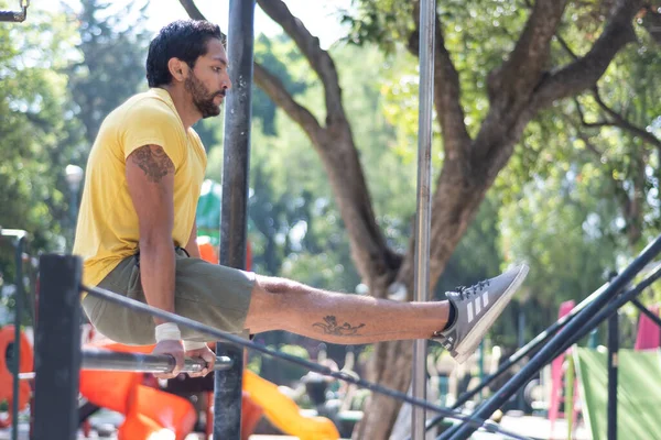 Genç adam parkta jimnastik yapıyor.