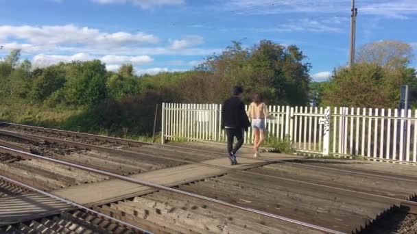 Двоє людей перетинають залізничний перевал Тонфорд Лейн поблизу Кентербері (Кент).. — стокове відео