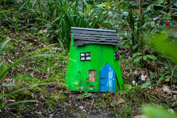 Şirin yeşil ahşap peri evi, İrlanda 'da büyüleyici bir peri bahçesinde orman zemininde mavi kapısı var..