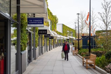 Erkek alışverişçi Ashford Outlet Center gezinti güvertesinde uyanıyor. Çoklu tasarımcı tabelaları görünür. 