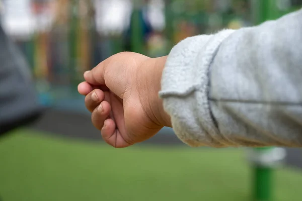 Close up view of childs outstretched hand reaching for something or someone in an outdoor setting.