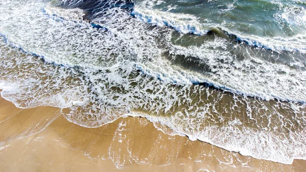 Aereo drone vista volo sopra le onde del mare che rotolano sulla riva sabbiosa. — Foto Stock