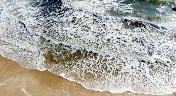 Aereo drone vista volo sopra le onde del mare che rotolano sulla riva sabbiosa. — Foto Stock