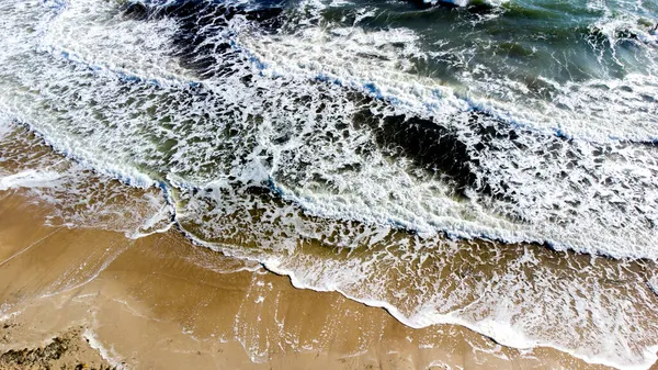 공중 무인기에서는 모래가 많은 해안으로 굽이쳐 흐르는 바 다 물결을 넘는 비행을 바라본다. — 스톡 사진