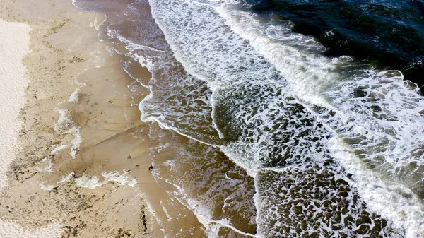 Avión teledirigido vuelo sobre las olas del mar que rodar sobre la orilla arenosa. —  Fotos de Stock