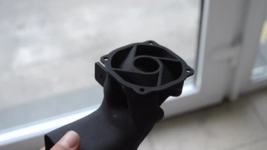 Podyum tozundan çıkan 3D yazıcıya basılmış plastik model tutan adam..
