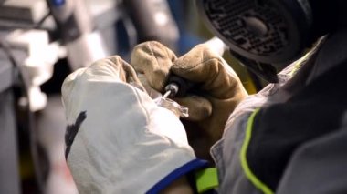 Metal parçalayan işçiler yakın plan çekimde. Eldivenleri elle takan kişi