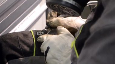 Metal parçalayan işçiler yakın plan çekimde. Eldivenleri elle takan kişi