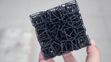 Podyum tozundan çıkan 3D yazıcıya basılmış plastik model tutan adam..
