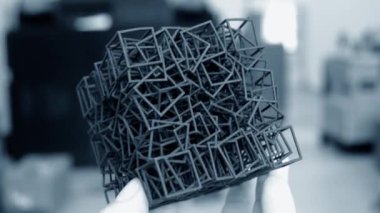 Podyum tozundan çıkan 3D yazıcıya basılmış plastik model tutan adam..