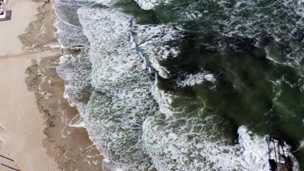 มุมมองโดรนทางอากาศบินเหนือคลื่นทะเลที่ม้วนลงบนชายฝั่งทราย . — วีดีโอสต็อก