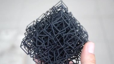 Kişi elinde 3D yazıcıya basılmış bir nesne tutar.