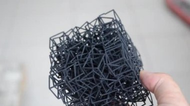 Kişi elinde 3D yazıcıya basılmış bir nesne tutar.