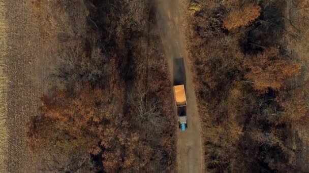 Vuelo aéreo de la vista del dron sobre el tractor azul con el remolque lleno grano amarillo del maíz — Vídeos de Stock