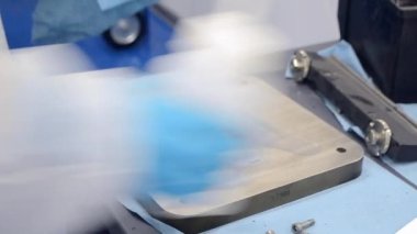 Beyaz Koruyucu Takım Giyen İşçi ve Mavi Koruyucu Eldiven Temizleyici Metal Parçası