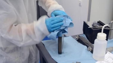 Beyaz Koruyucu Takım Giyen İşçi ve Mavi Koruyucu Eldiven Temizleyici Metal Parçası