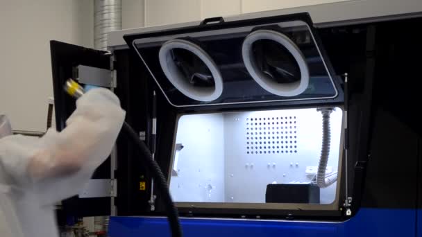 Pracovník v bílém ochranném obleku čistí vnitřní průmyslovou 3D tiskárnu pro kov — Stock video
