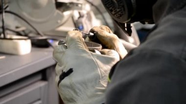 İş üniformalı bir adam, metal parçalarını yakın plan çekimle öğütür. Öğütücü metal detayı